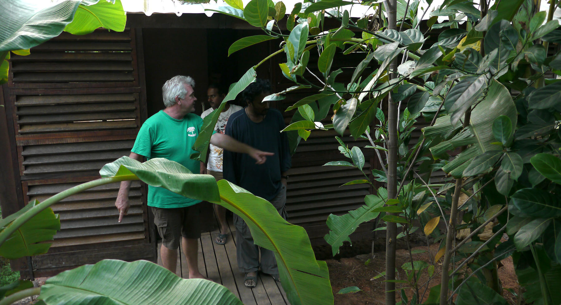 A course facilitator instructing at the Kagal field station, seen through banana-leaf foliage